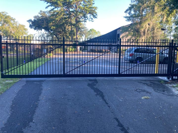 Black ornamental double driveway gate across a commercial entrance.